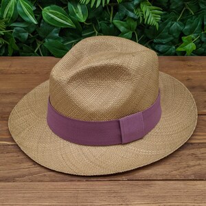 May include: A tan straw hat with a wide brim and a purple ribbon band.