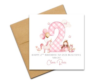May include: A birthday card featuring a pink gingham number 2, balloons, a unicorn, a princess, and a dragon. The card reads "Happy 2nd Birthday to our beautiful Niece! Clara Rose."