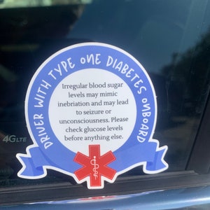May include: Blue and white sticker with the text "Driver with Type One Diabetes Onboard". The sticker has a red star of life symbol in the center. The text reads "Irregular blood sugar levels may mimic inebriation and may lead to seizure or unconsciousness. Please check glucose levels before anything else."