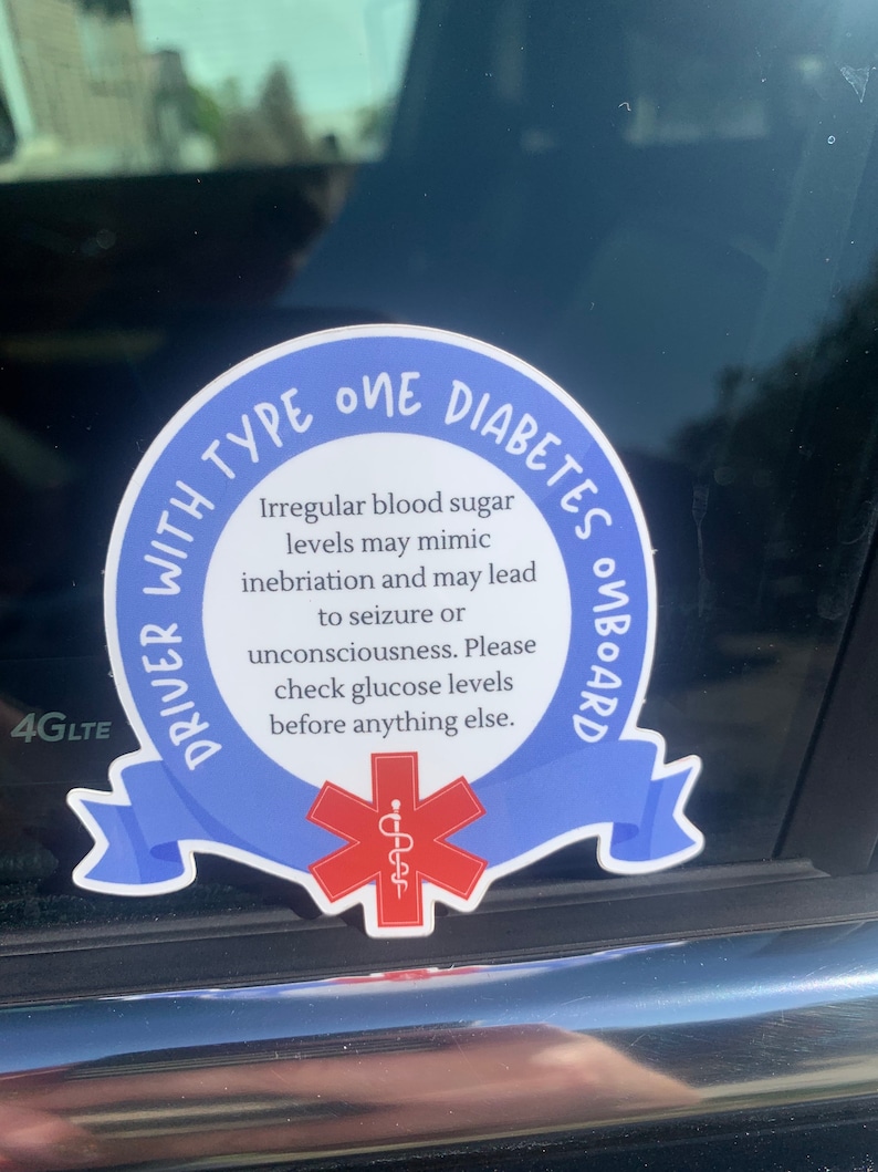 May include: Blue and white sticker with the text "Driver with Type One Diabetes Onboard". The sticker has a red star of life symbol in the center. The text reads "Irregular blood sugar levels may mimic inebriation and may lead to seizure or unconsciousness. Please check glucose levels before anything else."
