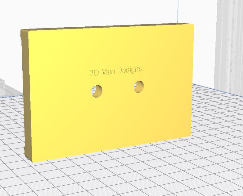 Op de afbeelding: Een geel rechthoekig object met twee cirkelvormige gaten. De tekst "3D Man Designs" is op het oppervlak gedrukt. Het object staat schuin, waardoor de dikte zichtbaar is.