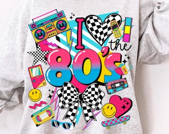 May include: A light gray sweatshirt with a colorful 80s-themed graphic. The design includes the text "I ❤️ the 80s" with a checkered heart, bow, and various retro icons like a boombox, cassette tape, and a handheld game console.