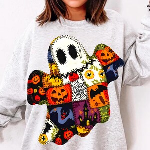 Pode incluir: Um moletom cinza claro com um design de fantasma de patchwork. O fantasma é composto por vários patches com tema de Halloween, incluindo abóboras, morcegos e teias de aranha. O fantasma tem um contorno costurado e olhos ovais pretos.