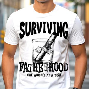 Pode incluir: Camiseta branca com um gráfico preto de um charuto em um copo de uísque com gelo. O texto diz: "SURVIVING FATHERHOOD ONE WHISKEY AT A TIME."