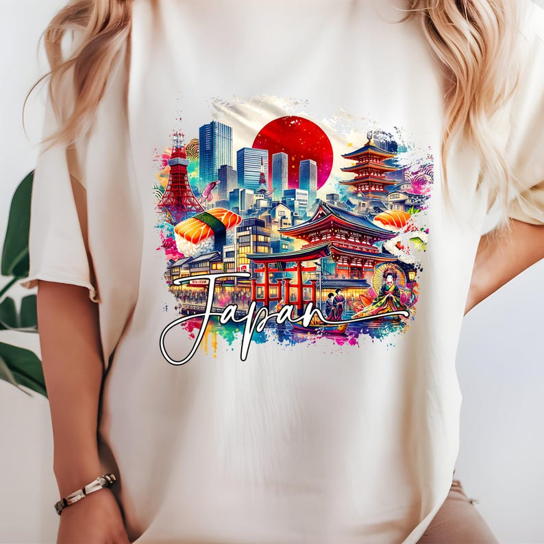 May include: Cream-colored t-shirt featuring a vibrant watercolor design of Japan. The graphic includes iconic landmarks, sushi, and a rising sun, with the word "Japan" in a cursive font. The design is colorful and detailed.