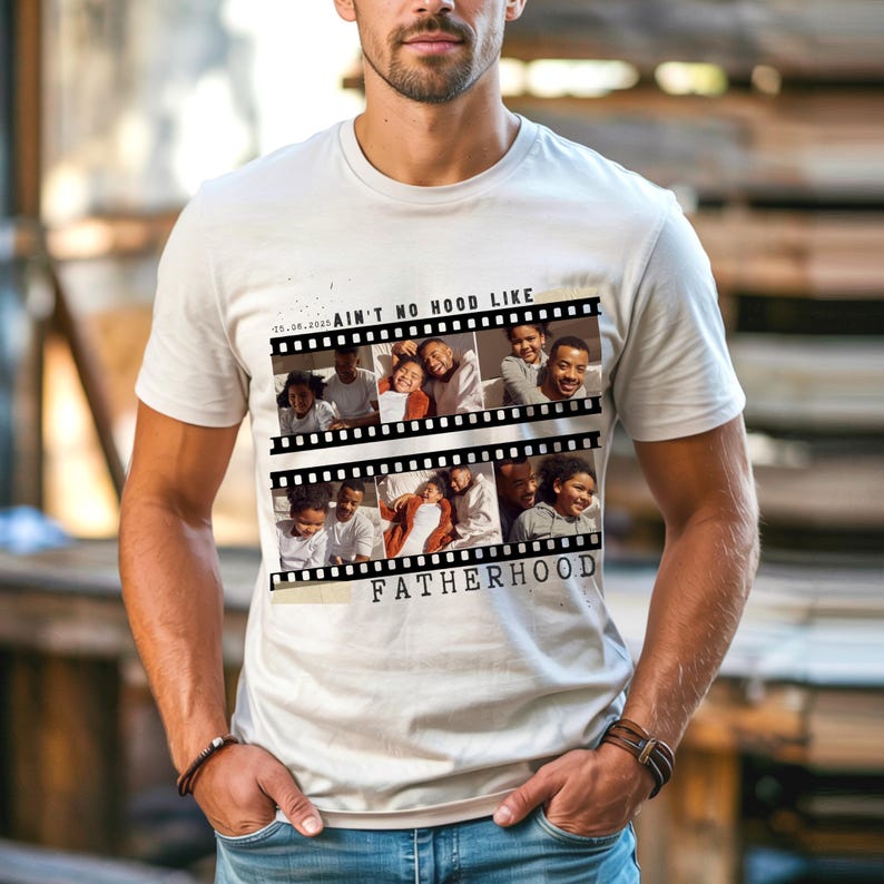 Pu&ograve; includere: Una maglietta beige chiaro con un design a striscia di pellicola con foto di famiglia. Il testo "AIN'T NO HOOD LIKE FATHERHOOD" &egrave; stampato sulla maglietta. La maglietta &egrave; a maniche corte e ha uno scollo tondo.