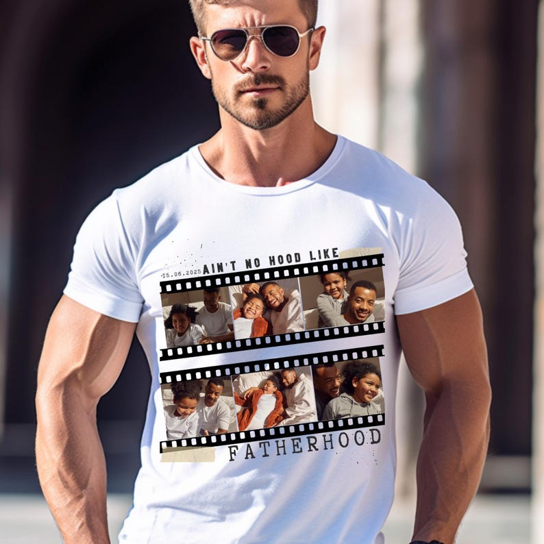 Pu&ograve; includere: T-shirt bianca con un design a striscia di pellicola con foto di famiglia. Il testo sulla maglietta recita "Ain't No Hood Like Fatherhood" e include la data "25.06.2025".