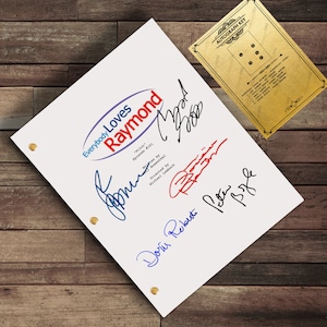 May include: A white script titled "Everybody Loves Raymond" with multiple signatures in blue and red ink. The script has gold eyelets and is next to a gold-colored autograph key.