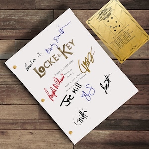 Puede incluir: Un guion blanco con el título "Locke & Key" y firmas en varios colores. El guion está sujeto con broches dorados. Una tarjeta dorada de llave de autógrafos está en la esquina superior derecha.