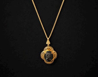 black cameo locket/gold tone against black background