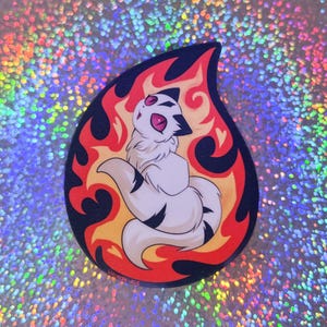 May include: A sticker featuring a cartoon white creature with black markings and pink eyes, set against a backdrop of stylized flames in red, orange, and black. The sticker has a teardrop shape and a holographic background.
