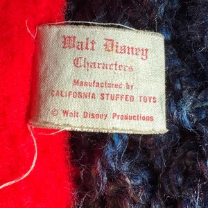 Op de afbeelding: Een wit label met zwarte tekst dat "Walt Disney Characters Manufactured by California Stuffed Toys &copy; Walt Disney Productions" zegt.