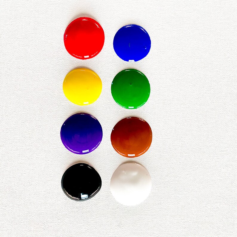 以下が含まれることがあります： ふた付きの丸い絵の具の容器が8つ、4つずつ2列に並んでいます。色は赤、青、黄、緑、紫、茶色、黒、白です。