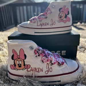 May include: White high-top sneakers with pink Minnie Mouse characters and the name "Layken Jo" written in pink glitter.