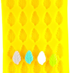 May include: A yellow silicone mold with 24 leaf-shaped cavities. Four leaf-shaped candies are in the mold, one is white, one is light blue, one is green, and one is gray.