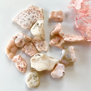 May include: A collection of pink and white polished stones with a variety of shapes and sizes. The stones have a natural, organic look and are perfect for use in crafts or as decorative elements.