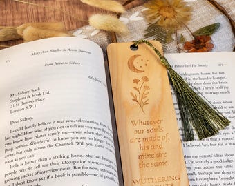May include: Wooden bookmark with a crescent moon, stars, and floral design, with the quote "Whatever our souls are made of, his and mine are the same. Wuthering Heights." A green tassel hangs from the top.