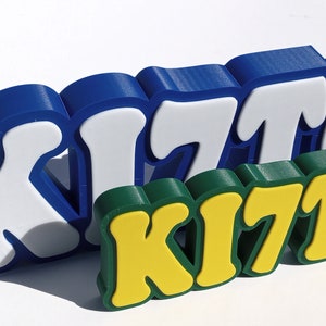 May include: Three dimensional, colorful, plastic letters spelling out the word "KITCJ" in blue, white, green, and yellow.