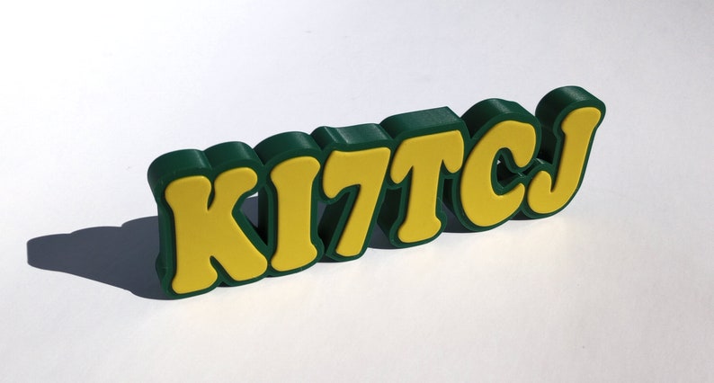 May include: A green and yellow 3D word sign that reads "KITCJ".