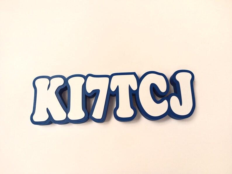 May include: White letters spelling "KITCJ" with a blue outline. The letters are in a bold, rounded font.