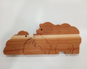 May include: A wooden puzzle depicting a family of sheep. The puzzle is made up of five pieces, each featuring a different sheep. The sheep are all brown with white markings. This puzzle is a fun and educational toy for children.
