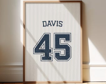 May include: A rectangular framed wall art print featuring a white background with thin vertical grey stripes. The center displays the name DAVIS in dark blue block lettering above the large dark blue number 45 with a distressed texture.