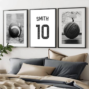 May include: A set of three framed black and white sports-themed prints. One features a football on grass, another displays the name "SMITH" and the number "10", and the third shows a basketball on a court.