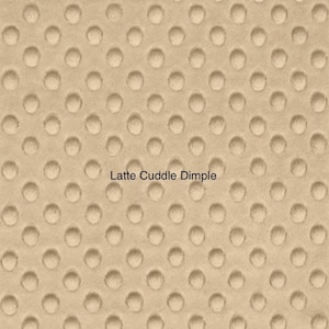 May include: Close-up of a beige fabric with a textured pattern of small, evenly spaced circles. The fabric is labeled "Latte Cuddle Dimple".