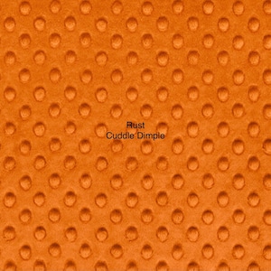 May include: Close-up of rust-colored fabric with a dimpled texture. The fabric has a repeating pattern of small, rounded indentations. The words "Rust Cuddle Dimple" are printed on the fabric.