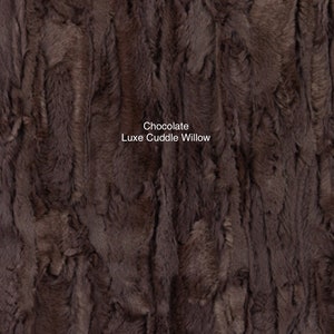 May include: Close-up of a brown faux fur fabric with a soft, fluffy texture. The fabric is called "Chocolate Luxe Cuddle Willow".
