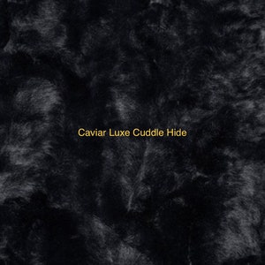 May include: Close-up of a black faux fur fabric with a soft, plush texture. The fabric is called "Caviar Luxe Cuddle Hide".