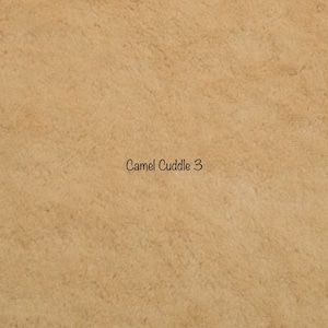 May include: A close-up of a tan fabric with a soft, textured appearance. The words "Camel Cuddle 3" are printed in a simple, black font in the center of the image. The fabric has a plush, inviting look.