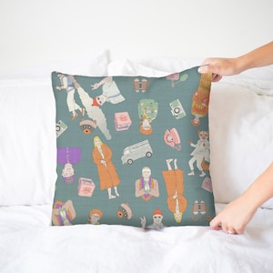 Puede incluir: Una almohada de tiro azul turquesa con un patrón repetitivo de personas, objetos y animales ilustrados. El patrón incluye una camioneta, binoculares, un teléfono, un gato y una persona con un sombrero rojo.