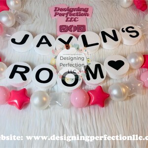 Puede incluir: Letras decorativas blancas y rosas que deletrean "JAYLN'S ROOM" con una letra "O" en forma de coraz&oacute;n. Las letras est&aacute;n rodeadas de cuentas blancas y rosas.