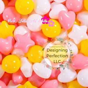 Puede incluir: Primer plano de un mont&oacute;n de juguetes de pl&aacute;stico de colores en forma de corazones, estrellas y c&iacute;rculos. Los juguetes son rosas, amarillos y blancos. El texto "Designing Perfection LLC" es visible en la imagen.