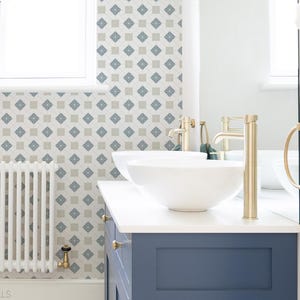May include: A blue bathroom vanity with a white countertop and a white porcelain sink. The vanity has two doors and two drawers. The bathroom has white tile floors and a white tiled wall with a geometric pattern. The text "West Coast Walls" is visible on the floor.