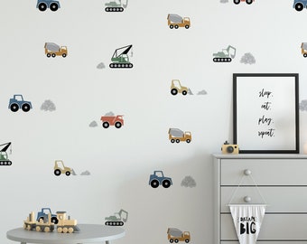 May include: A white wall with a repeating pattern of colorful construction vehicles, including dump trucks, cement mixers, and excavators. The wall is decorated with gray clouds. The room features a gray dresser, a small gray table and chair, and a gray basket.