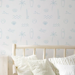 May include: A white nursery wallpaper with a light blue pattern of palm trees, surfboards, waves, seashells, and eyes. The wallpaper is shown in a room with a wooden bed, a wooden dresser, and a wooden toy house.