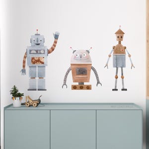 May include: Three watercolour robot wall decals in a light blue, brown and grey colour scheme. The robots are in various poses and have different facial expressions. The decals are on a white wall.