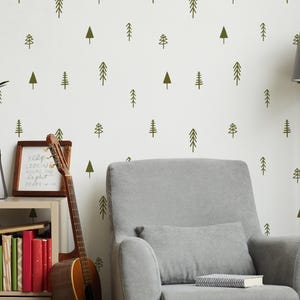 May include: A living room with a grey armchair, floor lamp, and a bookshelf. The white wall has a repeating pattern of green tree illustrations. A guitar leans against the wall, adding a musical touch to the decor. A clock and framed art are also visible.
