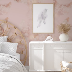 Può includere: Una cassettiera bianca con una texture di venatura del legno chiara e una parete rosa chiaro con un design ad acquerello. La cassettiera ha un design semplice con un piano superiore piatto e sei cassetti. La parete ha un design astratto sottile in tonalità di rosa e bianco. Il testo 'WEST COAST WALLS' è visibile sulla cassettiera.