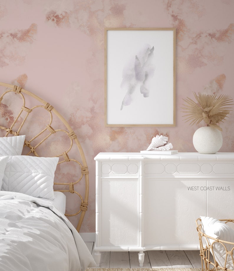 Può includere: Una cassettiera bianca con una texture di venatura del legno chiara e una parete rosa chiaro con un design ad acquerello. La cassettiera ha un design semplice con un piano superiore piatto e sei cassetti. La parete ha un design astratto sottile in tonalità di rosa e bianco. Il testo 'WEST COAST WALLS' è visibile sulla cassettiera.
