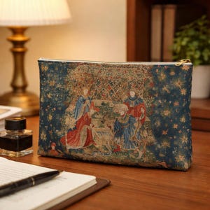 May include: A rectangular pouch with a zipper closure, featuring a tapestry design in shades of blue, red, and beige. The artwork depicts figures in medieval attire within a garden setting. The pouch has a gold-colored zipper and a white lining.