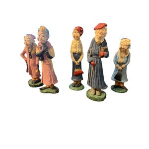 May include: A collection of five vintage figurines depicting elderly figures. The figurines are painted in various colors, including pink, blue, and yellow, and stand on green bases. Each figure is dressed in period clothing and accessories.