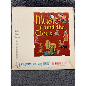 May include: A vintage vinyl record album cover with a red background and a colorful illustration of animals playing musical instruments. The title of the album is "Music 'Round the Clock" and the album is part of the "Together We Sing Series".