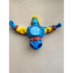 Puede incluir: Un torso de figura de acción de plástico azul y amarillo con un cinturón rojo y una abertura circular en el pecho. La figura no tiene cabeza ni piernas.