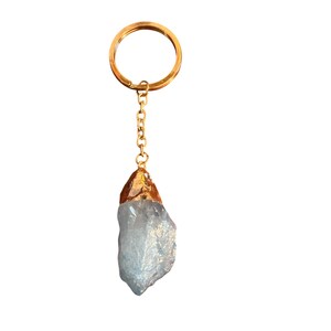 May include: A gold-toned keychain with a light blue crystal attached. The crystal is a natural, rough-cut shape.