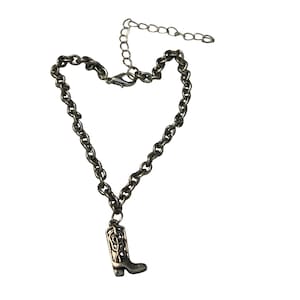 Op de afbeelding: Een zilveren enkelketting met een zilveren laarsbedel. De laarsbedel heeft een gedetailleerd ontwerp.