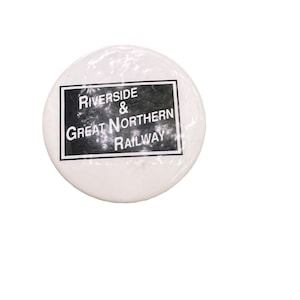 Peut inclure: Bouton blanc avec du texte noir qui dit "Riverside & Great Northern Railway".