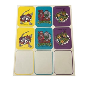 May include: A sheet of stickers featuring Teenage Mutant Ninja Turtles characters. The stickers are on a white background with yellow, blue, and purple borders. The stickers feature the Teenage Mutant Ninja Turtles characters in various poses, including fighting and holding weapons. The stickers also feature the text "Cowabunga!" and "Teenage Mutant Ninja Turtles".